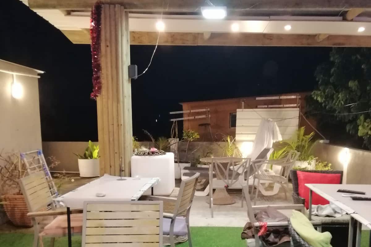 An outdoor patio area with tables and chairs, artificial grass, and potted plants.