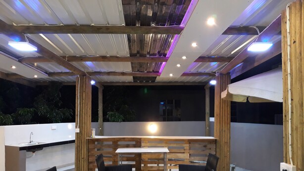 Un espace extérieur aménagé en terrasse, avec une table et des chaises en bois, un évier et une vue sur le ciel nocturne.