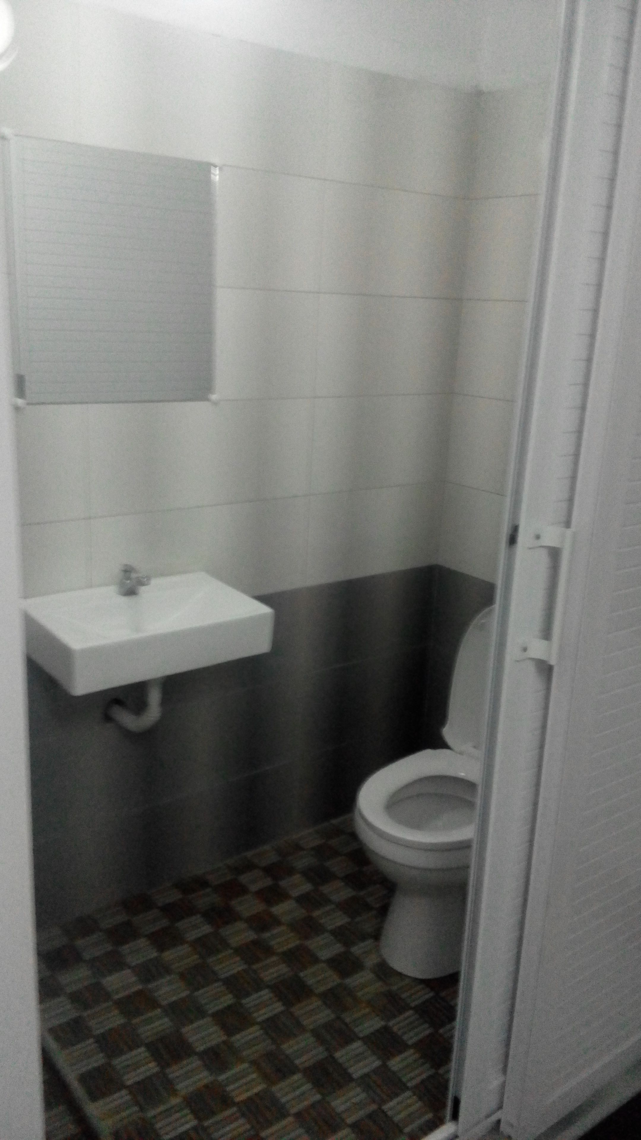 A small bathroom with a toilet, a sink, and a mirror.