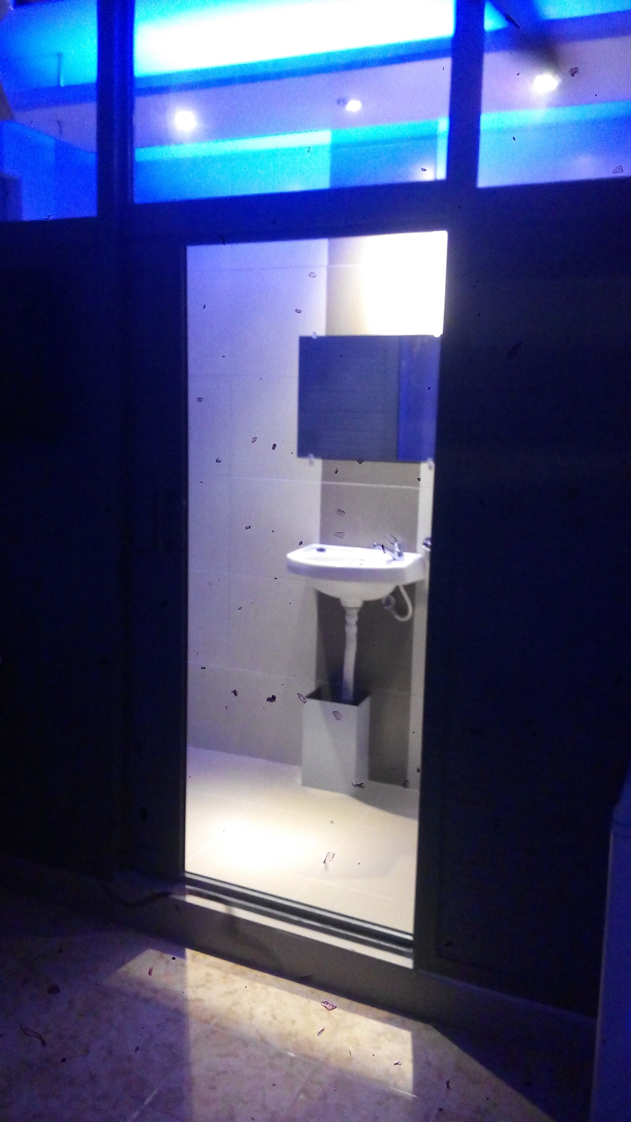 Un baño con un lavamanos blanco, un espejo encima y suelo de baldosas.