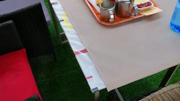 Ett bord dukat med frukostmat, inklusive ägg, rostat bröd, kaffe och juice, med utsikt över en gräsyta och stolar runt omkring.