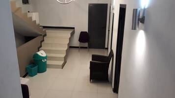 Un escalier menant à un palier où se trouvent une poubelle et une chaise.