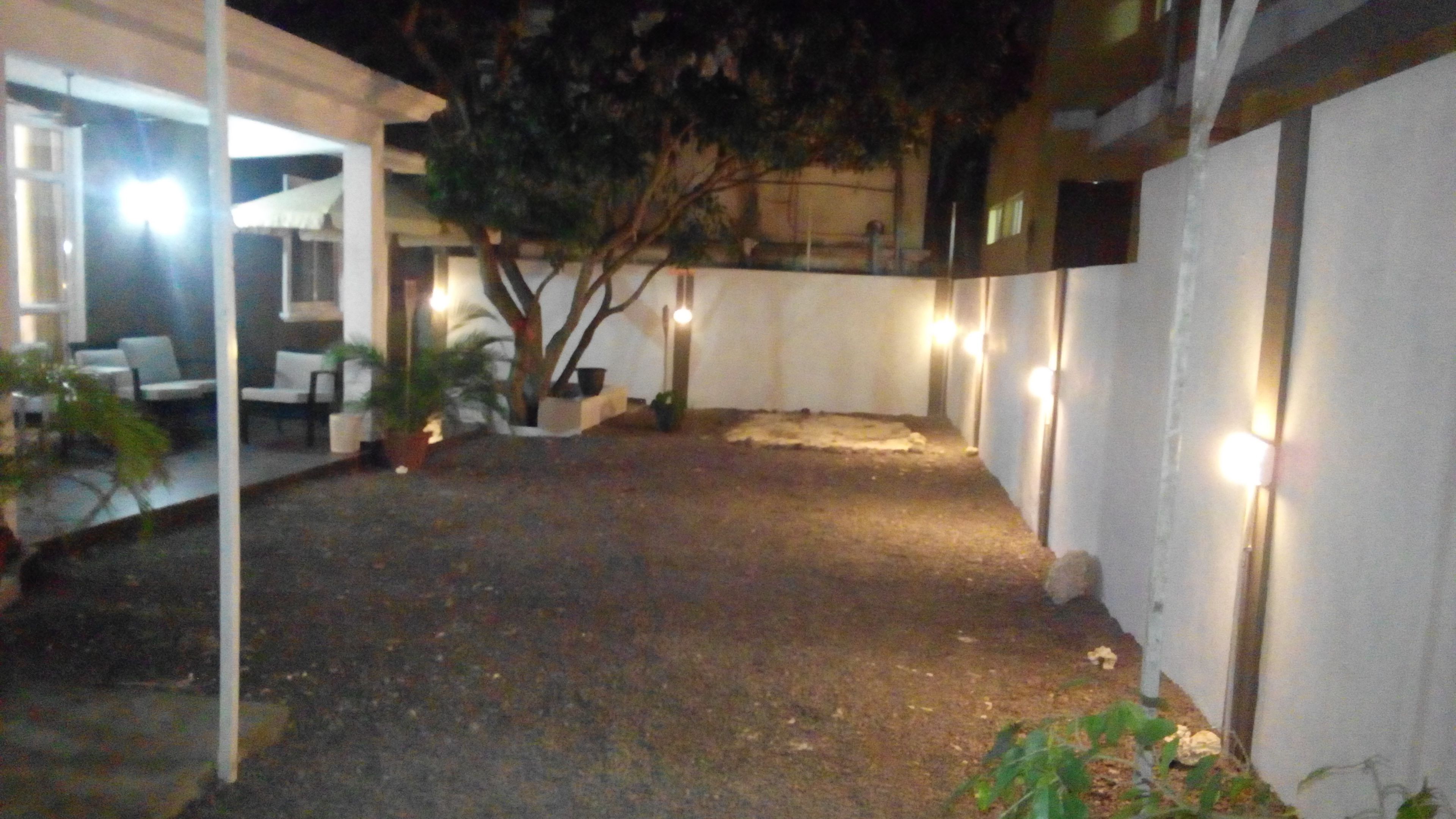 Um pátio com mobiliário e plantas em vasos, cercado por paredes e um edifício.