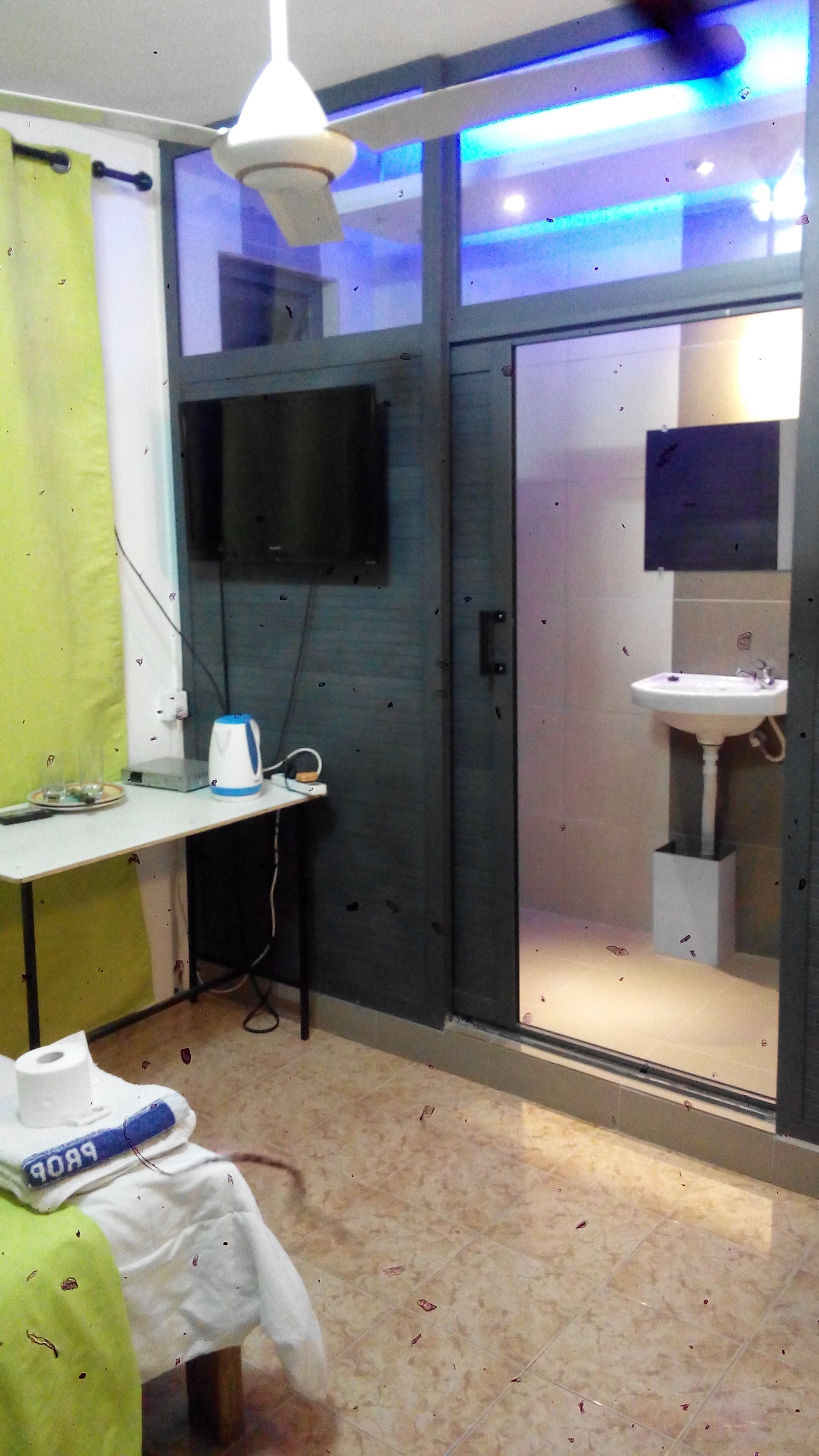 Un baño con lavamanos, espejo y televisión montada en la pared.