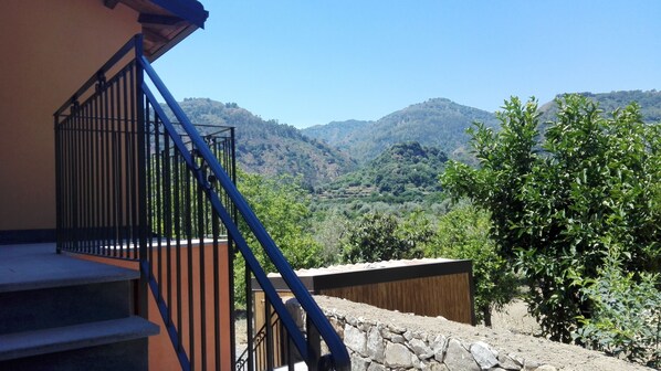 Una escalera con barandilla de metal que lleva a un balcón con vistas a un paisaje montañoso.