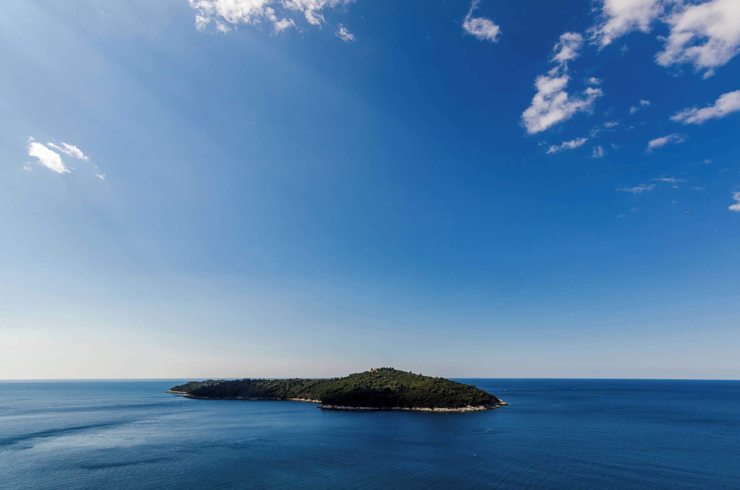 A small island with a clear blue sky and calm sea.