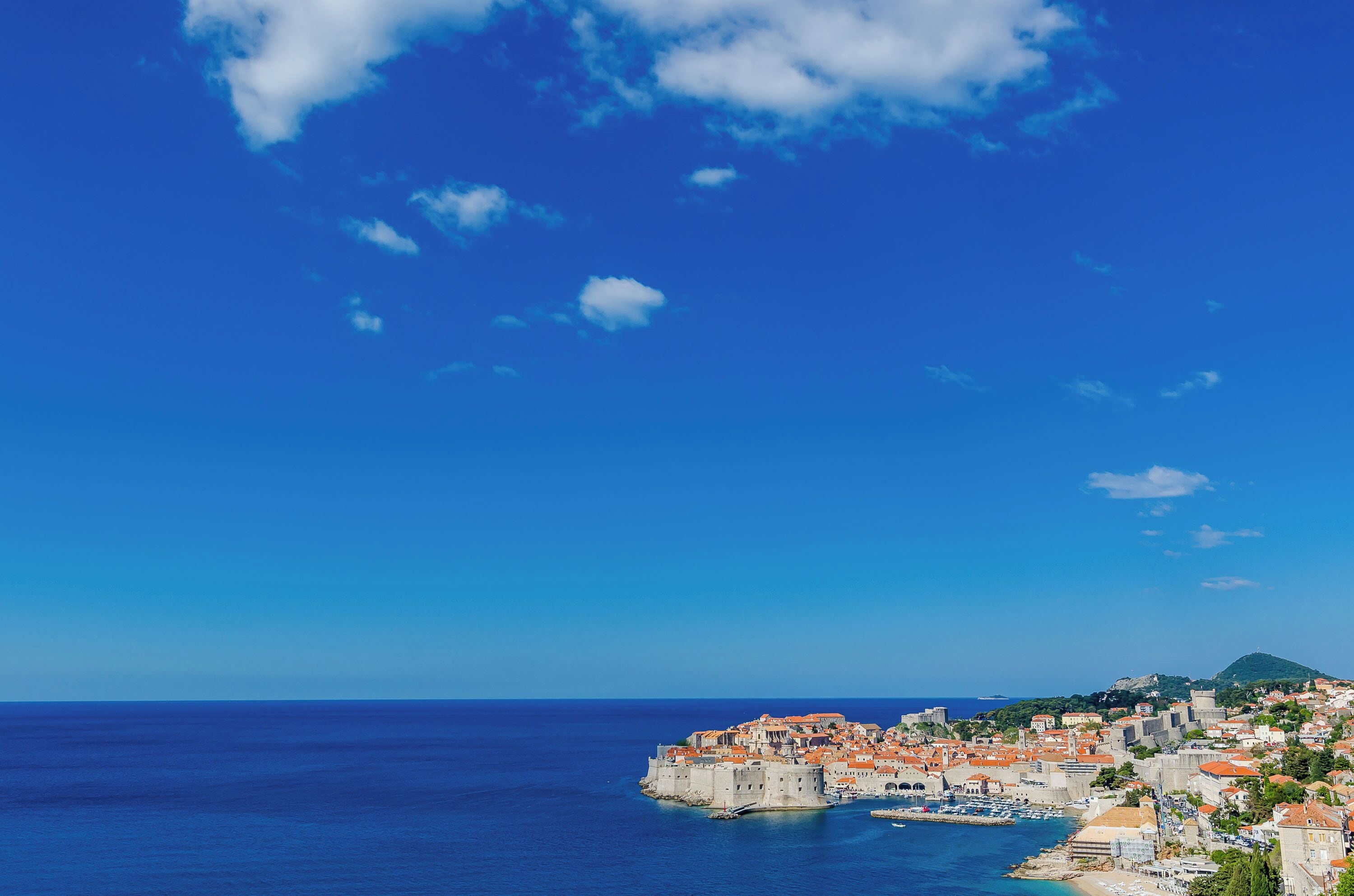 A coastal town with historic buildings, a fortified structure, and a clear blue sky.
