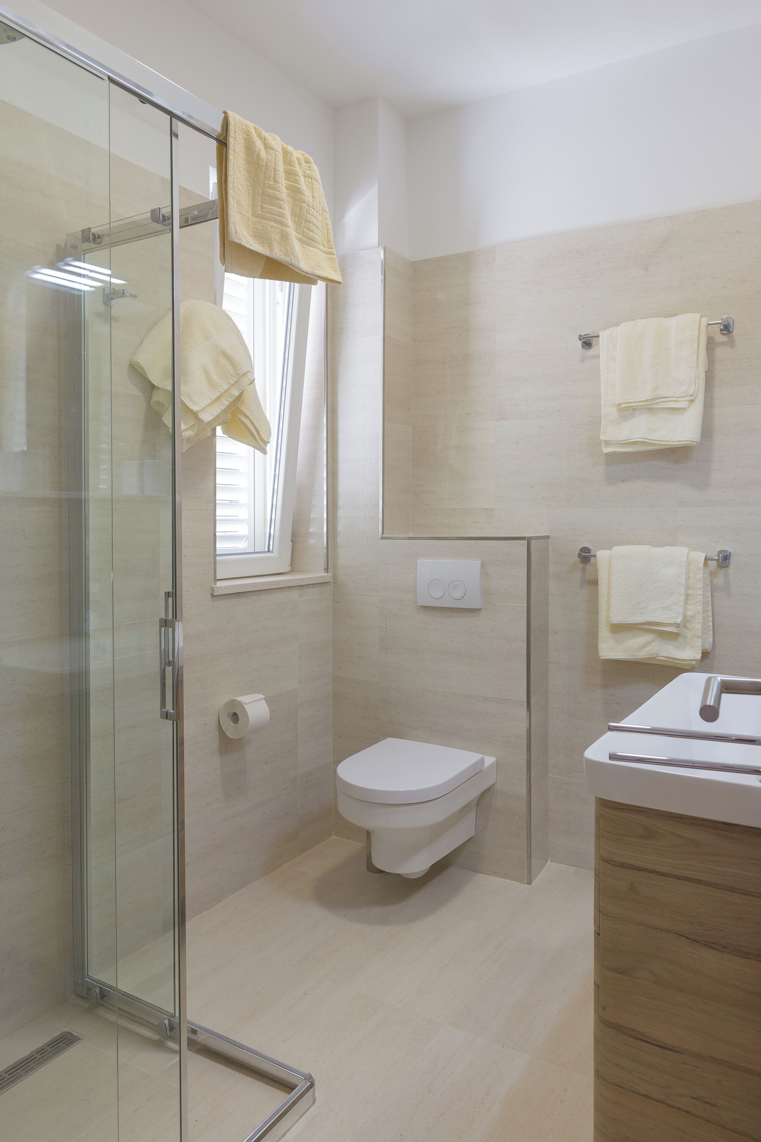 Um banheiro moderno com box de vidro, vaso sanitário e pia com armário de madeira.