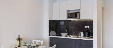 A modern kitchen with white cabinets, a black countertop, and a built-in microwave.
