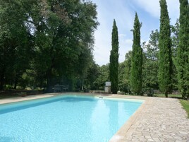 Una piscina al aire libre, sombrillas, sillones reclinables de piscina