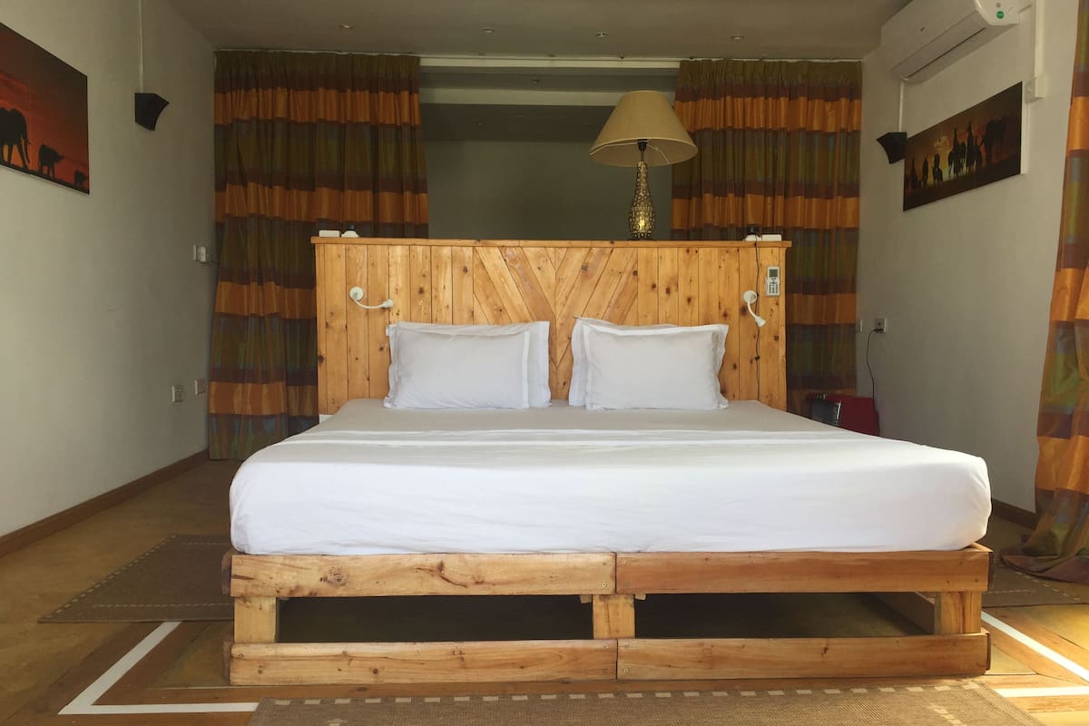 A room with a wooden bed frame, white bedding, and striped curtains.