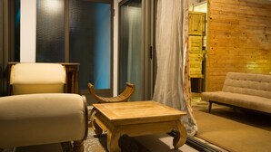 A living room with a sofa, armchair, wooden coffee table, and a small wooden side table. - Villa Alizée (Port Louis)