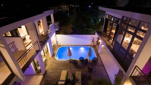Uma área de piscina no terraço com deck de madeira, espreguiçadeiras e guarda-sóis.