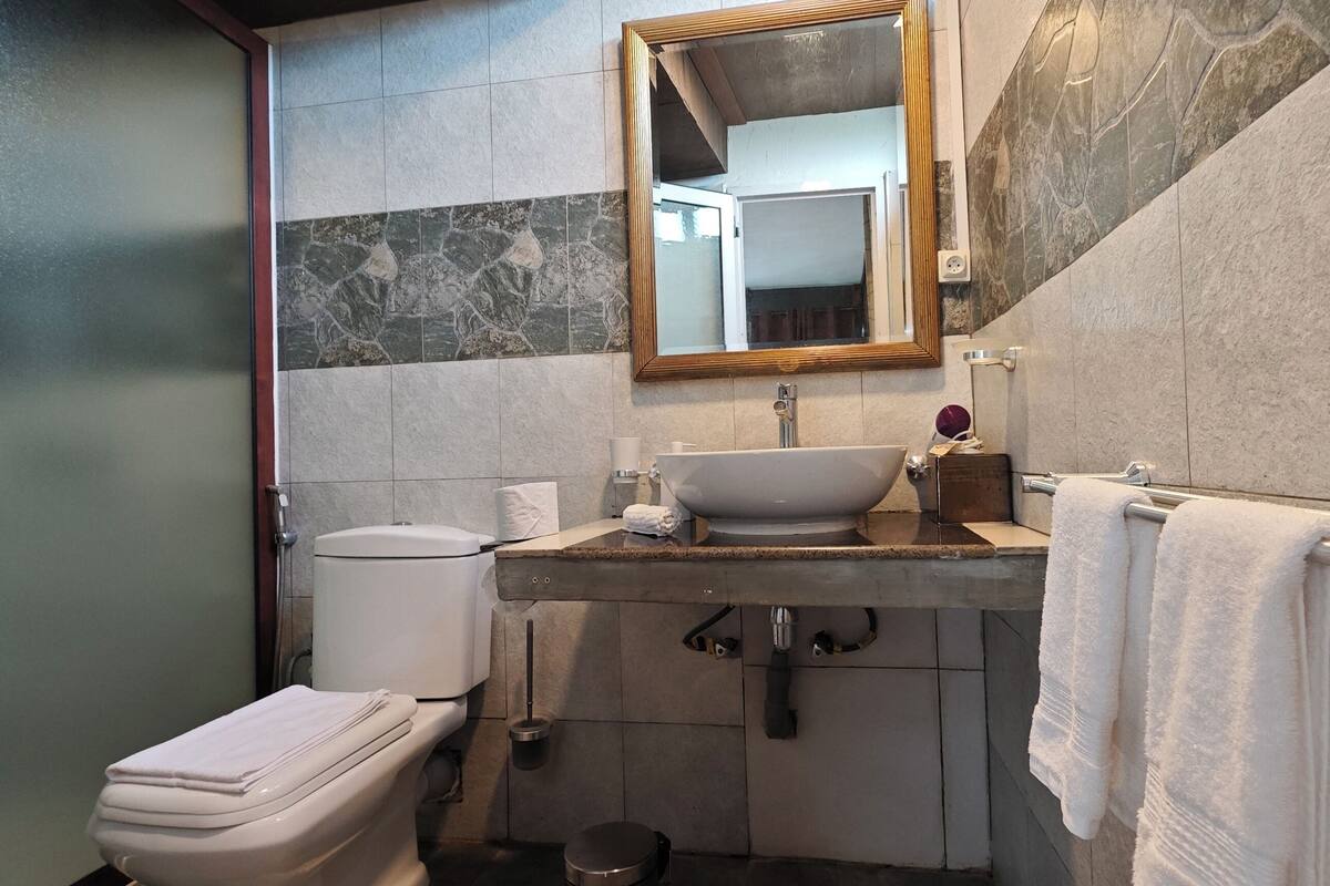 A bathroom with a toilet, sink, mirror, and towel rack.