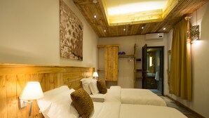 A hotel room with wooden paneling, two beds with white linens, a wall-mounted lamp, and a ceiling light. - Villa Alizée (Port Louis)