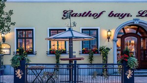 A building with a sign reading "Gasthof bayr, L" and a gate with a metal fence. - Hotel bayrischer Löwe (Osterhofen)