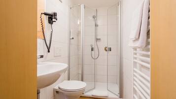 Ein kleines Badezimmer mit Waschbecken, Toilette und einer Duschkabine.