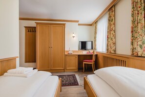 Una habitación de hotel con dos camas, un escritorio con silla, televisión y armario.