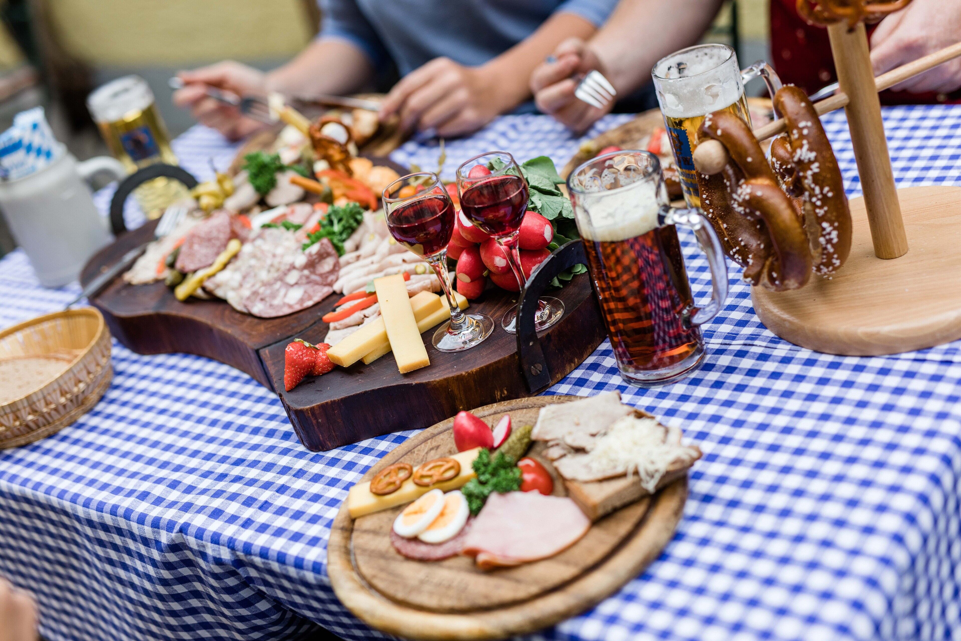 A table with a variety of food items and drinks, including sausages, cheese, and a beer mug.