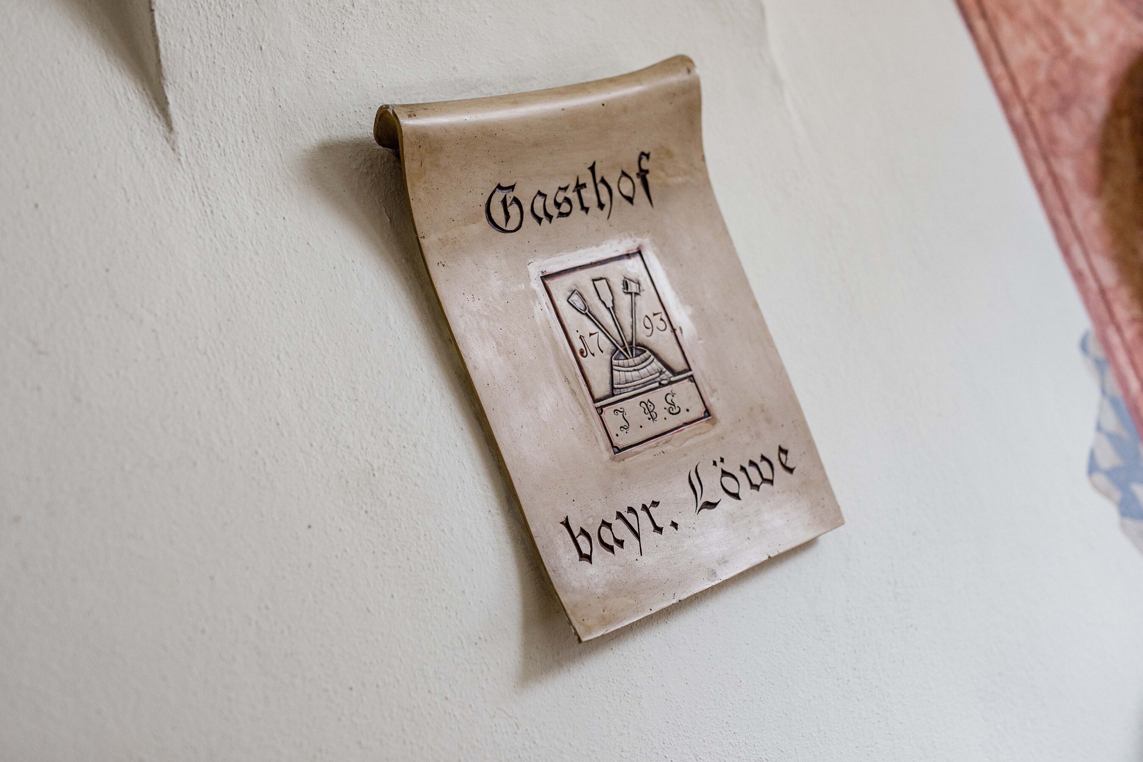 A parchment-like sign with the text "Gasthof" and "bav. Lüne" on a wall.