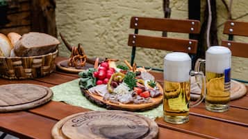A wooden table with a charcuterie board, two beer mugs, and bread.