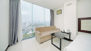 A modern hotel room with a large window, a sofa, a small table, and a bed. - Gemma Hotel & Apartment Near Dragon Bridge  (Da Nang)