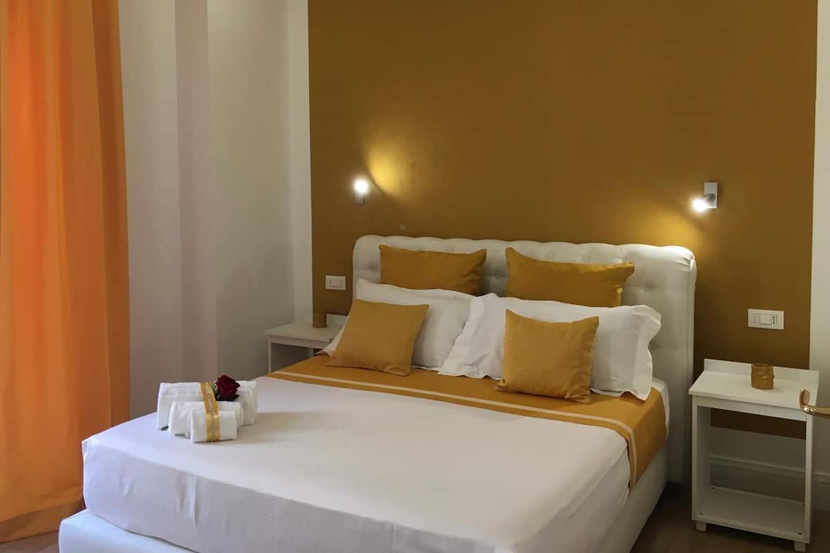 A hotel room with a large bed, two bedside tables, and a nightstand.