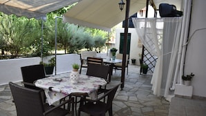 An outdoor patio with a table and chairs, surrounded by potted plants and a white wall. - Hotel Argo (South Pelion)