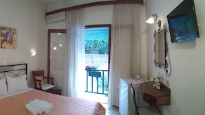 A hotel room with a bed, a chair, a desk, and a balcony with a view of greenery. - Hotel Argo (South Pelion)