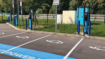 A parking area with electric vehicle charging stations, marked parking spaces, and directional arrows.