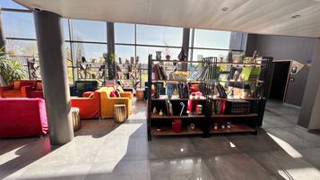 Um interior moderno com área de estar, estantes de livros e amplas janelas.