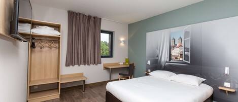 Un dormitorio con cama, escritorio, armario y ventana con cortinas.