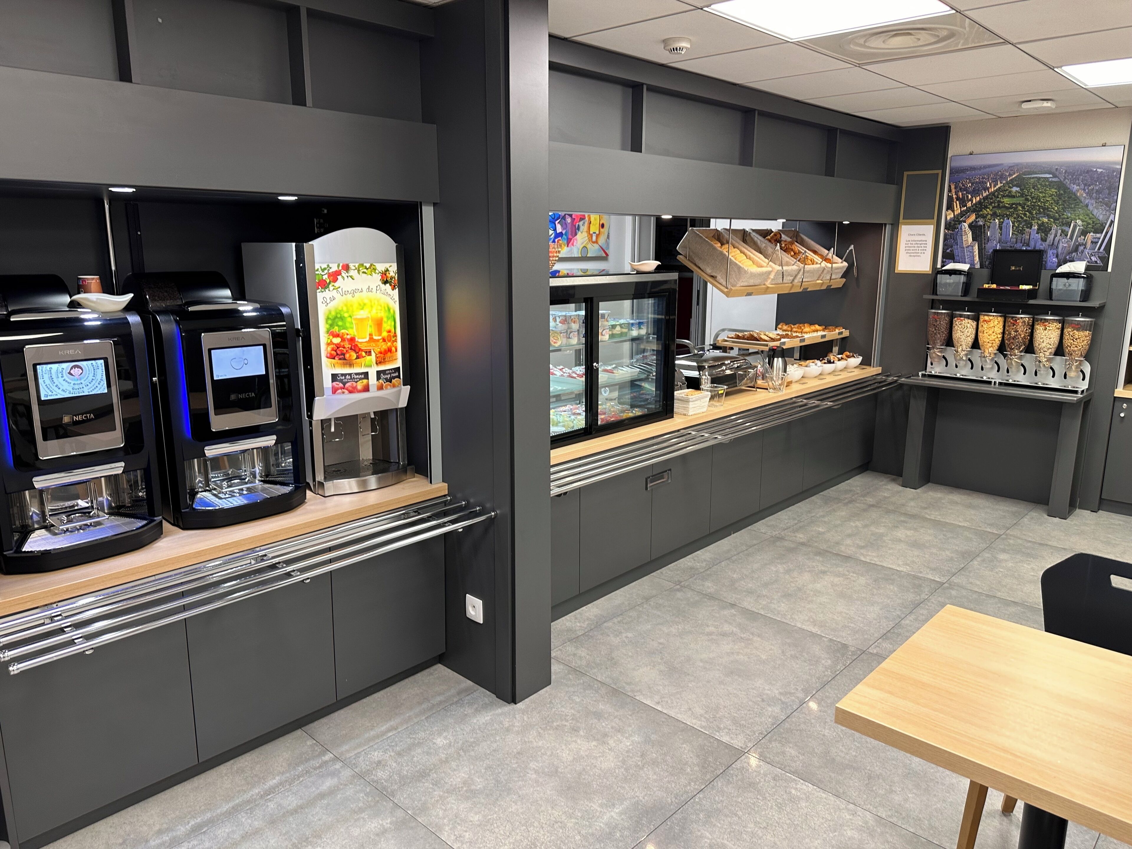 A modern café with self-service coffee machines, refrigerated display cases, and a variety of food items.