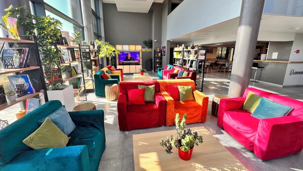 Un hall d’entrée spacieux, doté de meubles modernes, d’un téléviseur et d’un comptoir de réception.