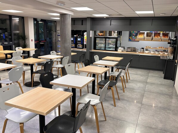 Un café moderno con varias mesas y sillas, una barra con productos a la vista y un amplio ventanal con vistas.