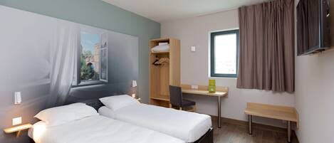 Habitación de hotel con dos camas, un escritorio, una silla, un televisor y una ventana con cortinas.