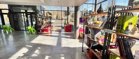 A modern interior with a glass door entrance, a red sofa, and a bookshelf with books and decorative items.