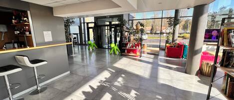 A modern lobby with a bar area, seating, and a large window providing a view of the outside.