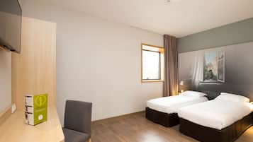 Hotelkamer met twee bedden, een bureau, een stoel, een televisie en een raam met gordijnen.