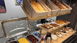 Un buffet proposant une variété de plats, notamment des pâtisseries, des viandes et des condiments.