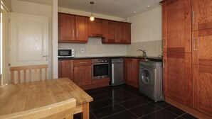 A kitchen with wooden cabinets, a microwave, an oven, a dishwasher, and a washing machine.