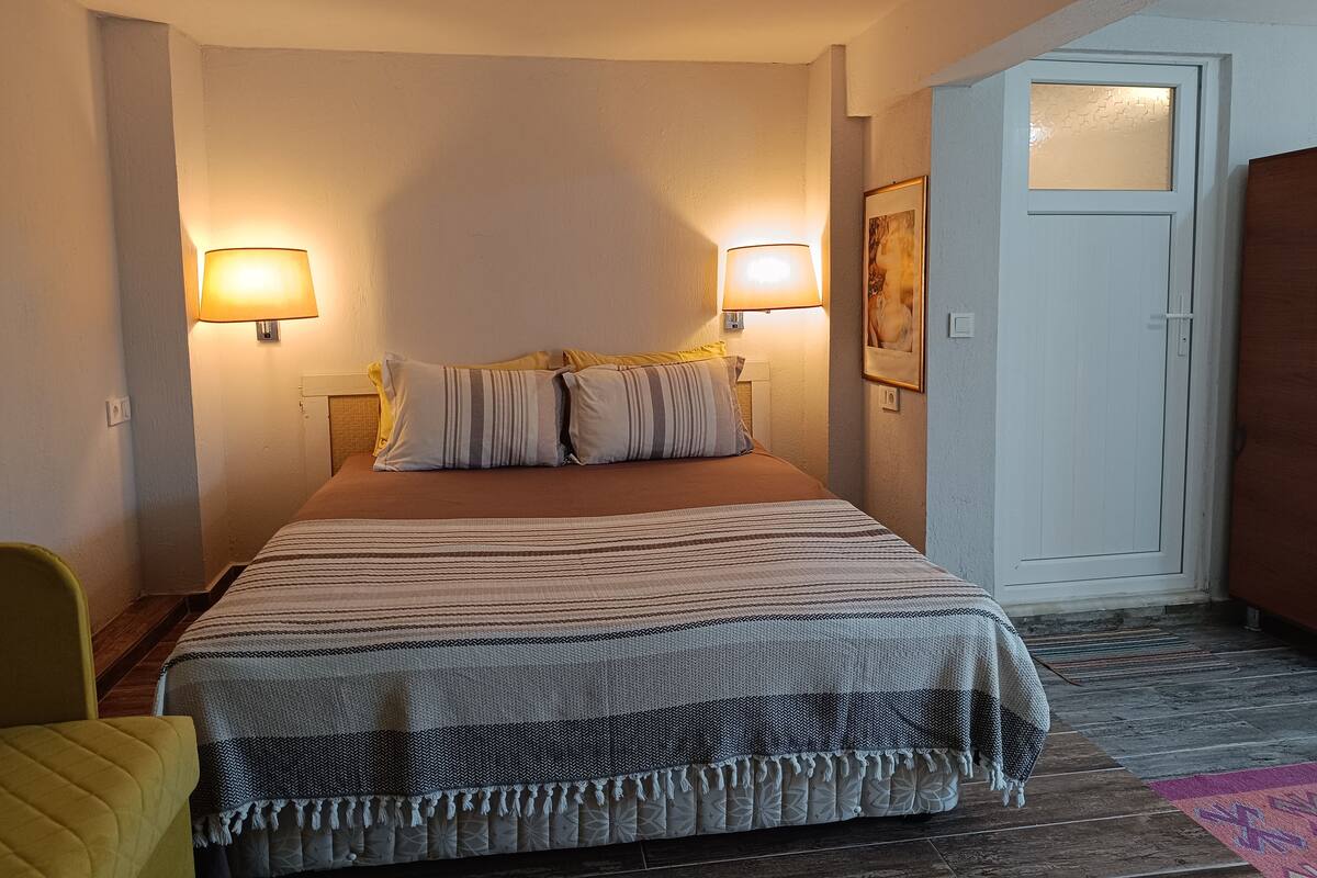 Ein Hotelzimmer mit einem Bett, zwei Nachttischlampen, einer Tür und einem Sessel.