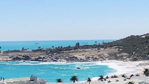 Un paysage côtier avec un terrain rocheux, une plage et un ciel dégagé.