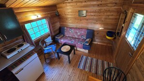 A cozy cabin interior with a wooden interior, a kitchenette, a sofa, and a dining area. - Tana Familiecamping (Tana)