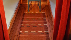 A cabin with a wooden interior, a central wooden chair, two beds, and a window with curtains. - Tana Familiecamping (Tana)