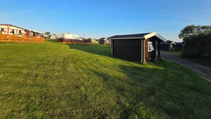 A campsite with a small wooden building, a caravan, and a grassy field. - Tana Familiecamping (Tana)