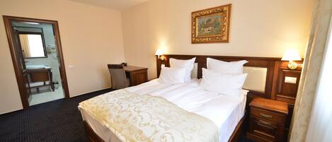 A hotel room with a large bed, bedside tables, a mirror, and an air conditioning unit.