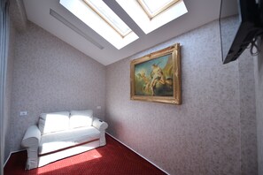Relax in this spacious room with a high ceiling, skylights, and a comfortable sofa.