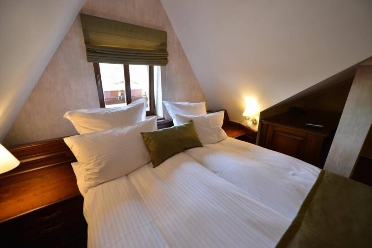 A bedroom with a bed, pillows, a window with a view, and a lamp.
