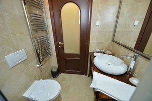 Un baño pequeño con inodoro, lavamanos y espejo.